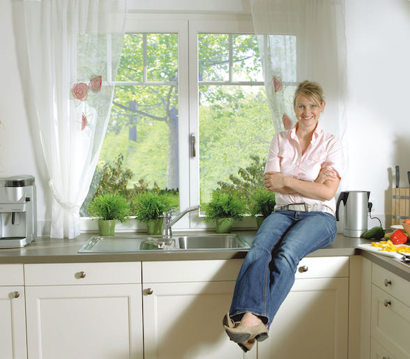 Kunststofffenster in der Küchenzeile mit stolzer Hausbesitzerin