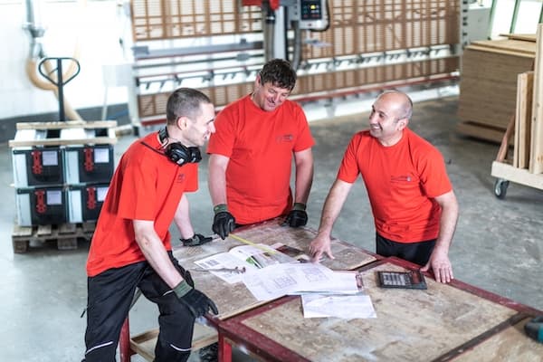drei maenner mit rotem t-shirt in einer werkstatt
